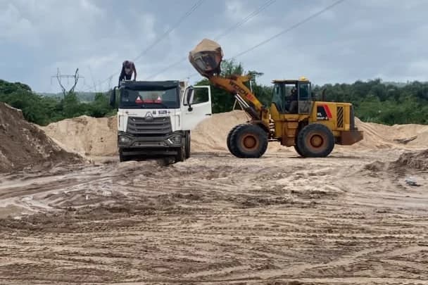 Loader and haul truck preparing sand for construction material delivery