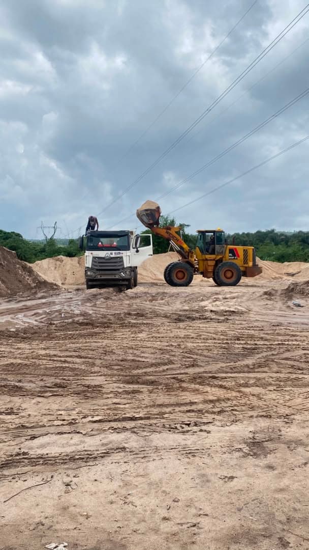 Loader and haul truck preparing sand for construction material delivery